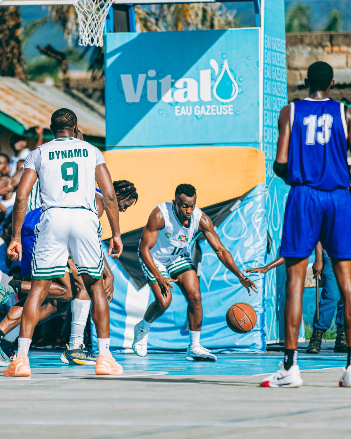 Un match de basket sur un terrain extérieur avec un panneau sponsor